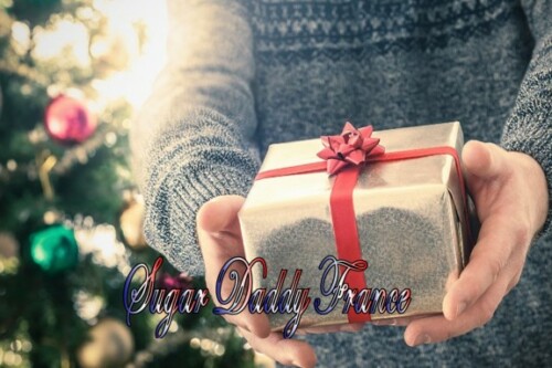 Mains avec cadeau de Noël et arbre de Noël en arrière-plan